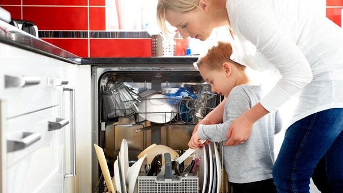 Une mère et son jeune enfant remplissent le lave-vaisselle.