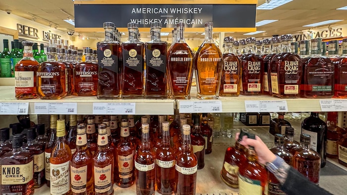 Une employée place des bouteilles de whisky américain sur des tablettes dans une succursale de la LCBO.