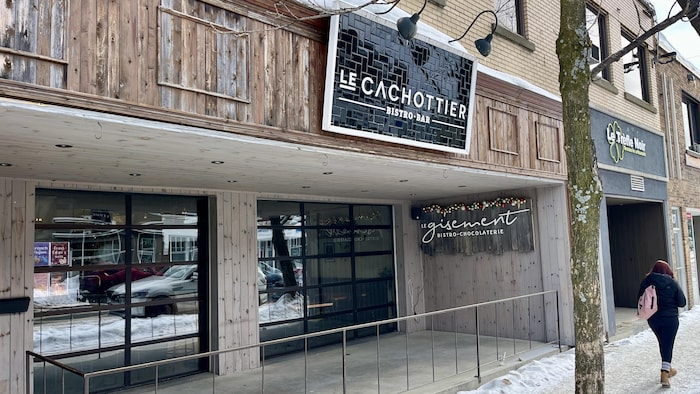La façade du bistro-bar Le Cachottier et une femme, de dos, qui passe devant.