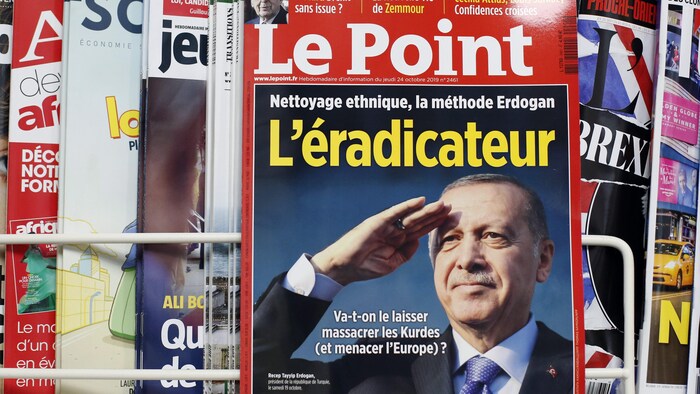 Le magazine Le Point est posé devant un étalage de magazines.