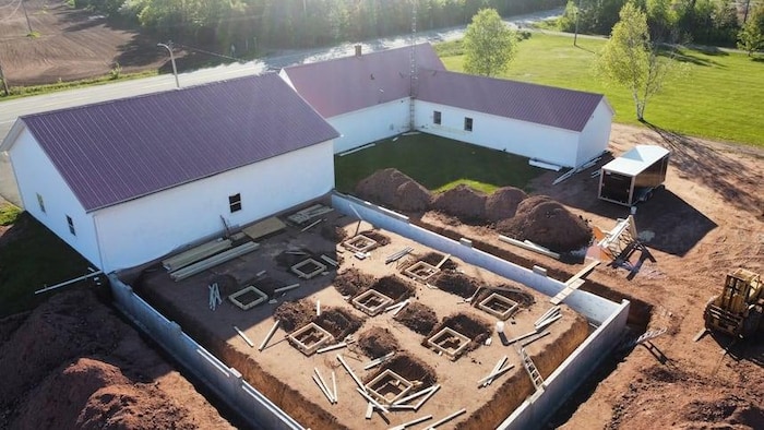 Photographie aérienne d'un chantier d'agrandissement d'un bâtiment lors d'une journée ensoleillée.