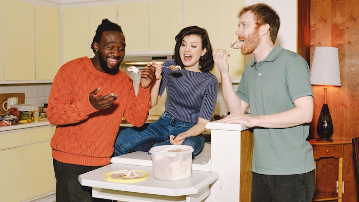 Les trois acteurs partagent un gâteau en riant.
