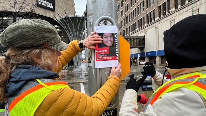 Des personnes collent des affiches de Leah Keeper dans le centre-ville de Winnipeg. (Photo d'archives)