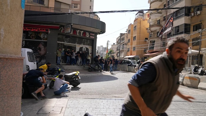 A man runs to take cover as supporters of a Shia group allied with Hezbollah fire weapons during armed clashes that erupted during a protest in the southern Beirut suburb of Dahiyeh. It was not immediately clear what triggered the gunfire.
