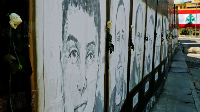 White roses are seen on portraits of victims of last year's Beirut port blast in the Lebanese capital.