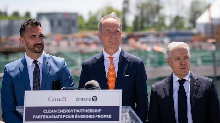 Stephen Lecce, Peter Bethlenfalvy et François-Philippe sur un scène lors de l’annonce sur le site du nouveau projet nucléaire de Darlington à Courtice en Ontario, le mardi 23 juin 2026.