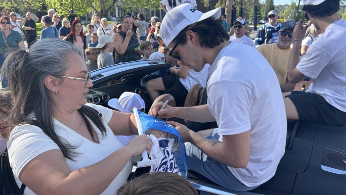 Un joueur signe un autographe dans un char allégorique.