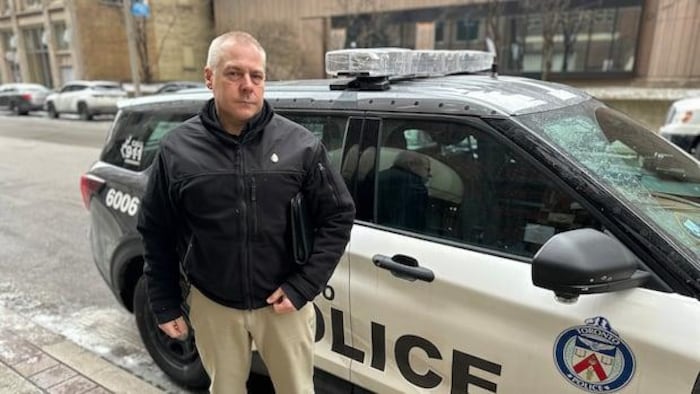 Jeff Bassingthwaite devant un véhicule de la police de Toronto.