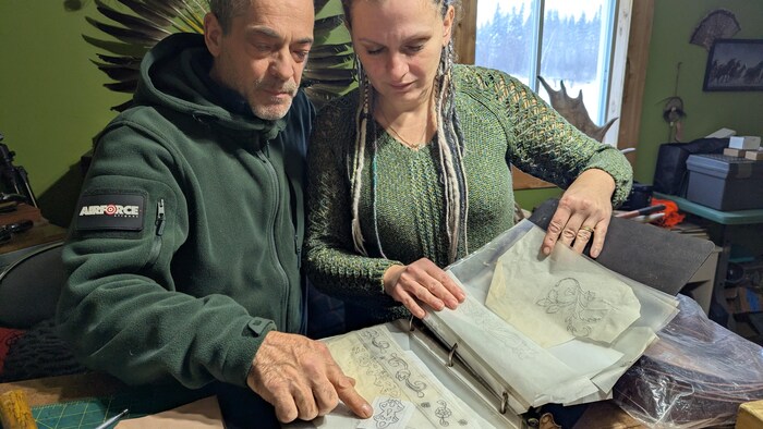 Les deux personnes sont penchées en regardant un livre avec des dessins.