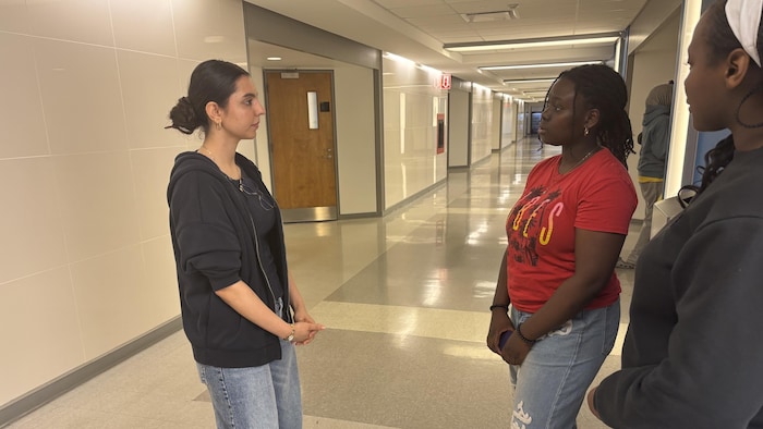 Une étudiante en médecine répond aux questions de deux élèves, dans un corridor de l'Université de Montréal.