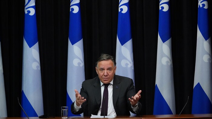 Le premier ministre François Legault assis, devant un micro.