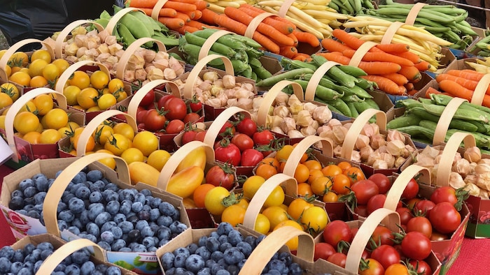 Des boites de fruits et de légumes sur une table d'un marché. 