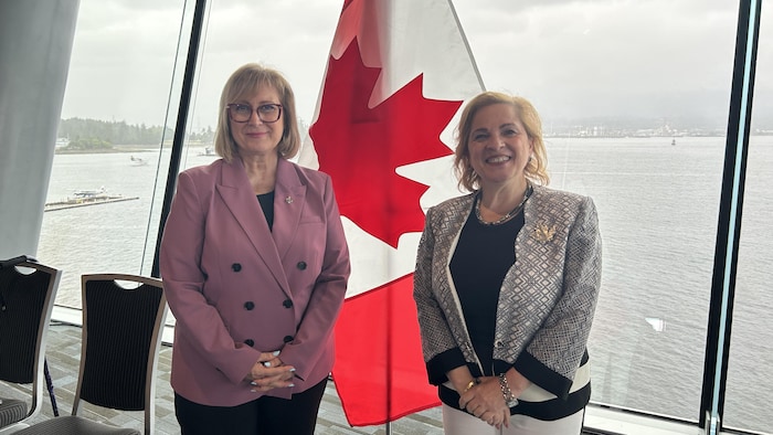 Les élues côte à côte, avec un drapeau canadien et la vue sur l'anse Burrard.