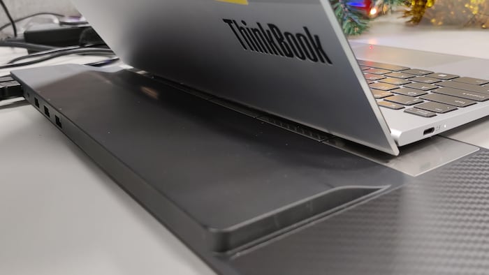 Un ordinateur portable au logo ThinkBook est posé sur un appareil noir de forme rectangulaire, muni de ports USB, entre autres.