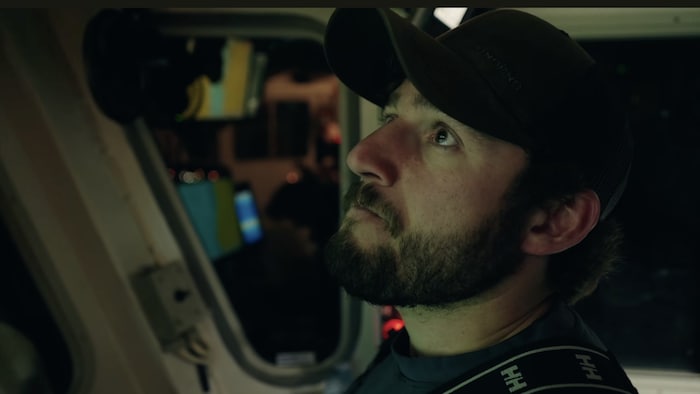 Un homme portant une casquette dans un bateau regarde vers le haut.