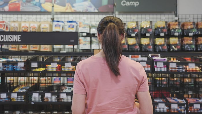 Une femme devant des tablettes remplies de produits de nutrition sportive.