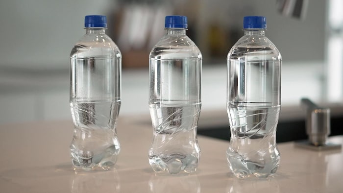 Trois bouteilles d'eau sur un comptoir.