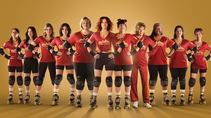 Portrait de l'équipe féminine de roller derby, les femmes alignées les unes à côté des autres avec les mains sur les hanches. 