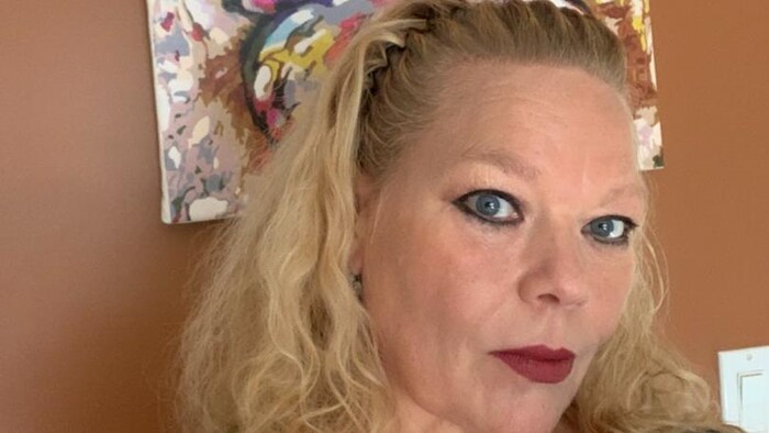 Lesa Chayer-Coutu se prend en photo devant un tableau coloré d’un papillon accroché sur un mur.