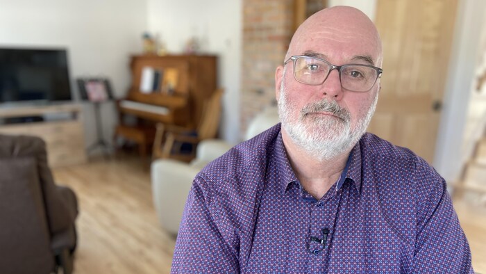 Un homme assis dans son salon.