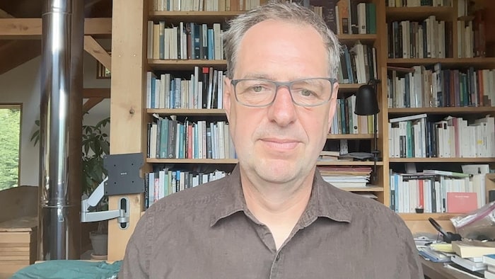 Éric Pineault devant sa bibliothèque.