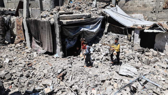 Des enfants transportent de la nourriture parmi les ruines.