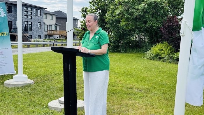 Joanne Gervais gives a speech. franco-ontarian flag now floating countryside
