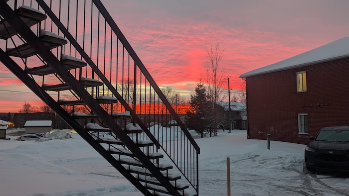 Un escalier dans un quartier résidentiel avec un ciel coloré au loin. 
