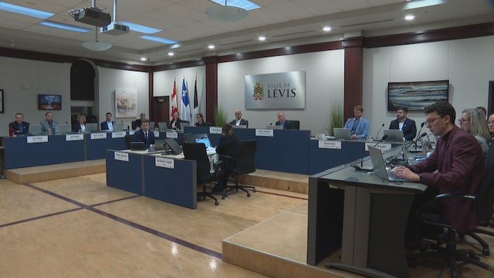 Les membres du conseil municipal de Lévis derrière leur bureau pendant une séance ordinaire du conseil municipal.