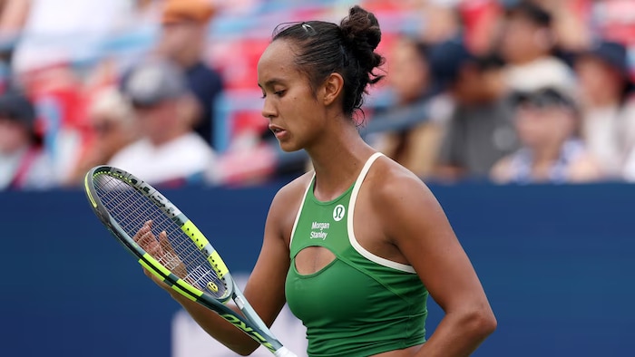 Une joueuse de tennis regarde sa raquette.