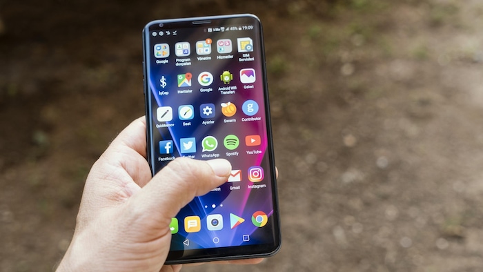Une personne tient dans sa main gauche un téléphone intelligent de la marque LG.