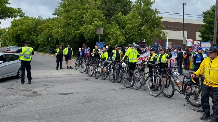 Des policiers avec des vélos au milieu de manifestants.