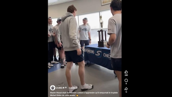 De jeunes hommes se tiennent autour d'un trophée.