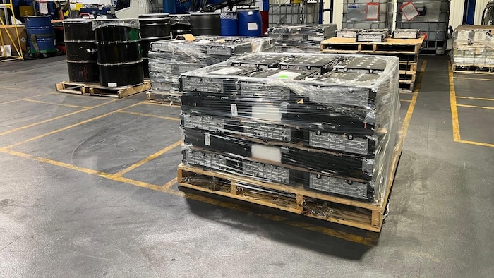 Des batteries sur une palette dans une usine.
