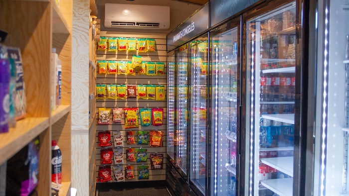 Des réfrigérateurs, des congélateurs et des étagères accueillent les produits du depanneur libre-service, comme des bonbons, des boissons et des articles de pharmacie.