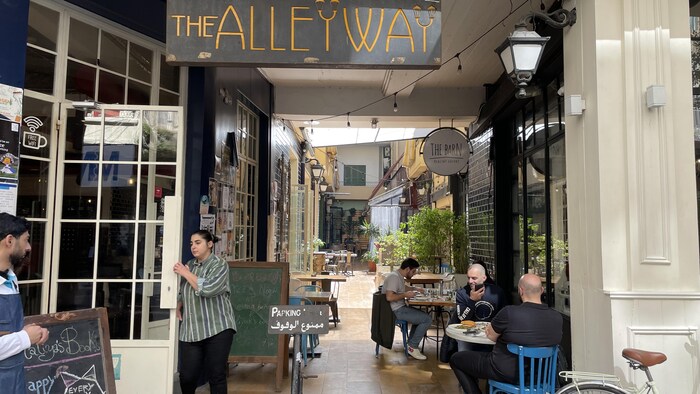 Quelques clients sont assis à l'extérieur d'un café dans une ruelle sans issue à Beyrouth.