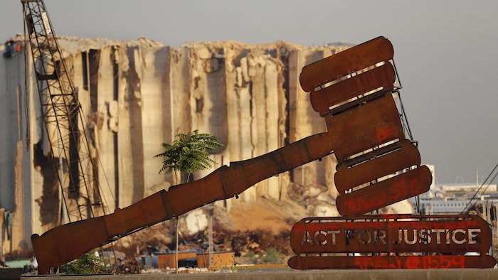 Un monument représentant un maillet avec l'inscription « Agir pour la justice » est installé devant les silos détruits du port de Beyrouth.
