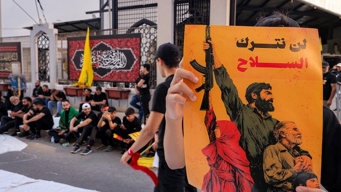 Une personne dans la banlieue sud de Beyrouth tient une pancarte sur laquelle on peut lire en arabe : «Nous n'abandonnerons pas les armes».