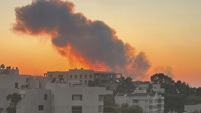 De la fumée s'élève dans le ciel, au-dessus de bâtiments.