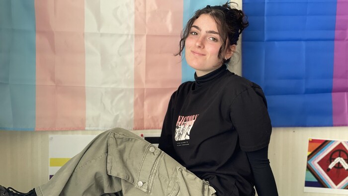 Une élève pose devant deux drapeaux de la fierté.
