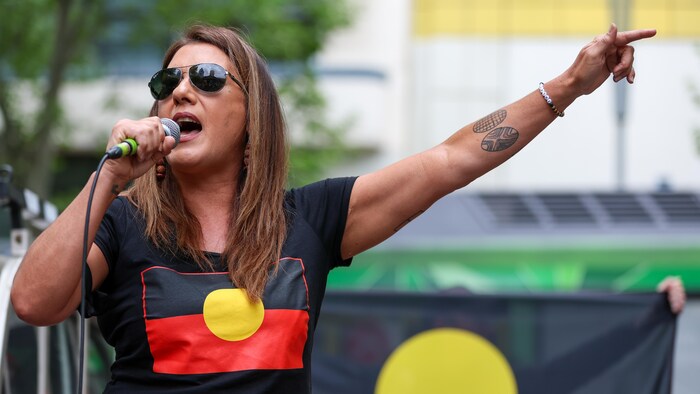 Lydia Thorpe holds a microphone and addresses a crowd at a protest. 