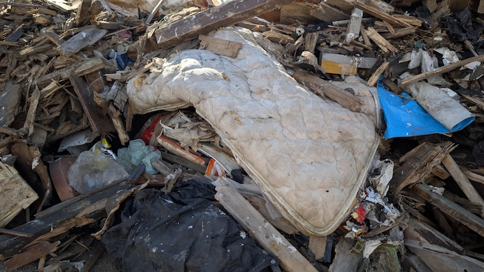 Un vieux matelas se trouve parmi les déchets.