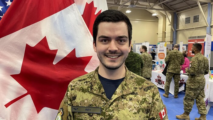 Le lieutenant Jérémy Roy dans son uniforme devant un drapeau canadien.
