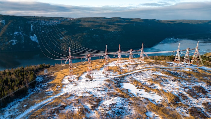Des lignes électriques traversent un fleuve pendant l'hiver.