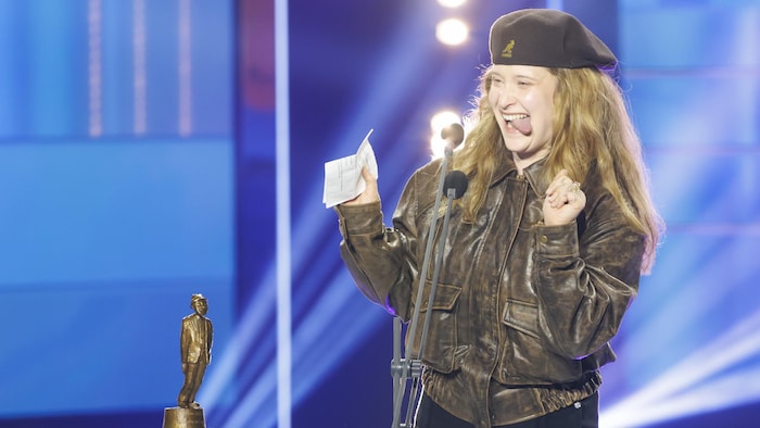 L'humoriste grimace sur scène à côté de son trophée. 