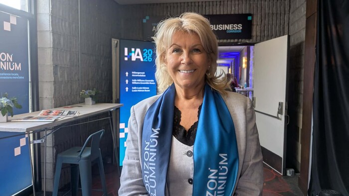 Une femme blonde sourit à la caméra.