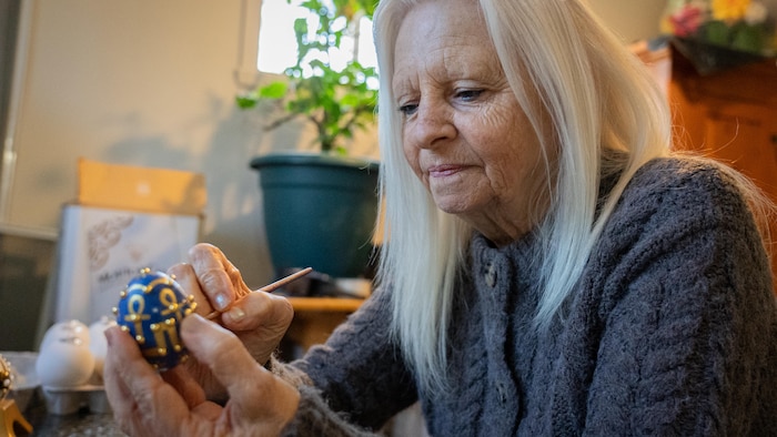 Une femme peint des pièces de céramique.