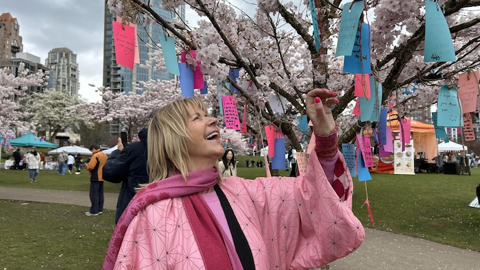 Linda Poole touche les fleurs d'un cerisier. 
