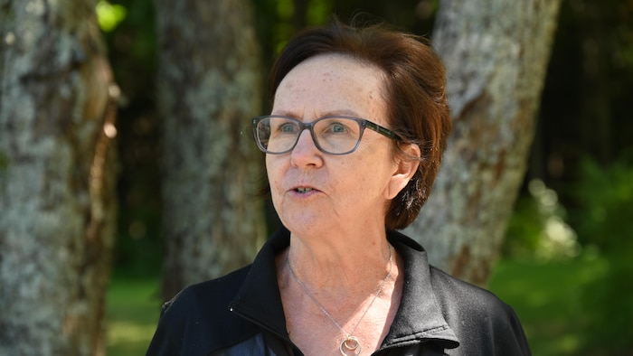 Linda Renaud en entrevue, à l'extérieur, près d'arbres.