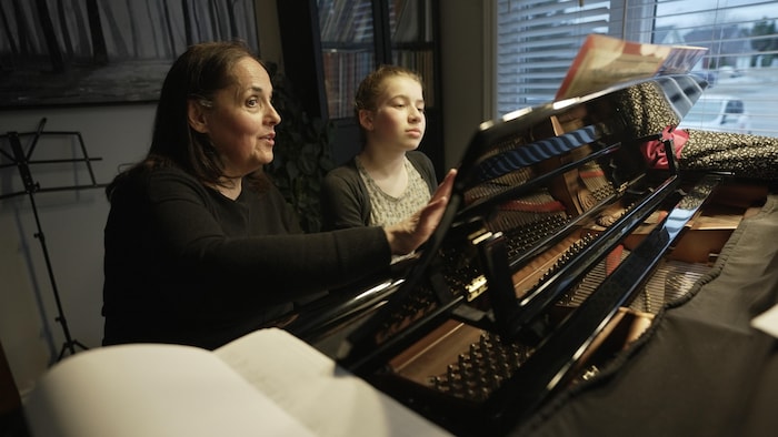 Line Fogal enseigne le piano à une jeune fille.